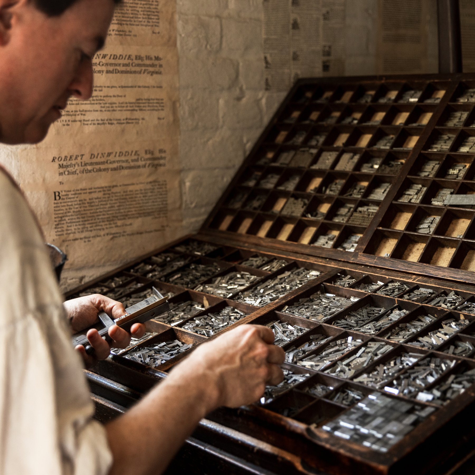 A photo of a printmaker looking for letters to set type.