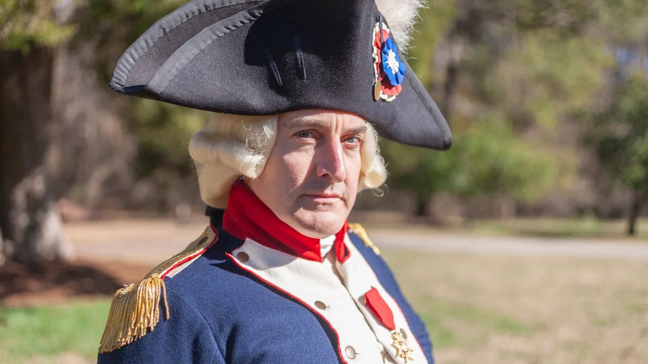 An interpreter dressed as Marquis De Lafayette smiles at the camera.