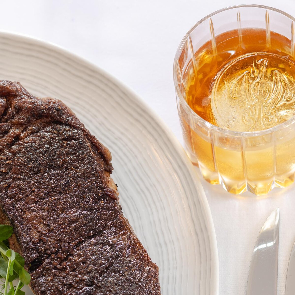 Bourbon (with ice etched with the Inn logo) and a New York Strip Steak served in the Rockefeller Dining Room at the Williamsburg Inn. September 30, 2024