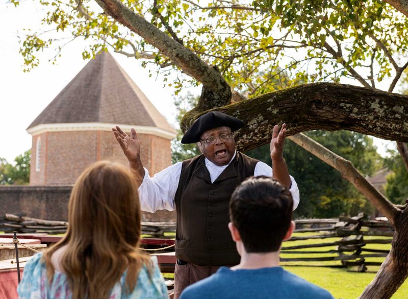 An interpreter dressed as Gowan Pamphlet speaks to a tour group.