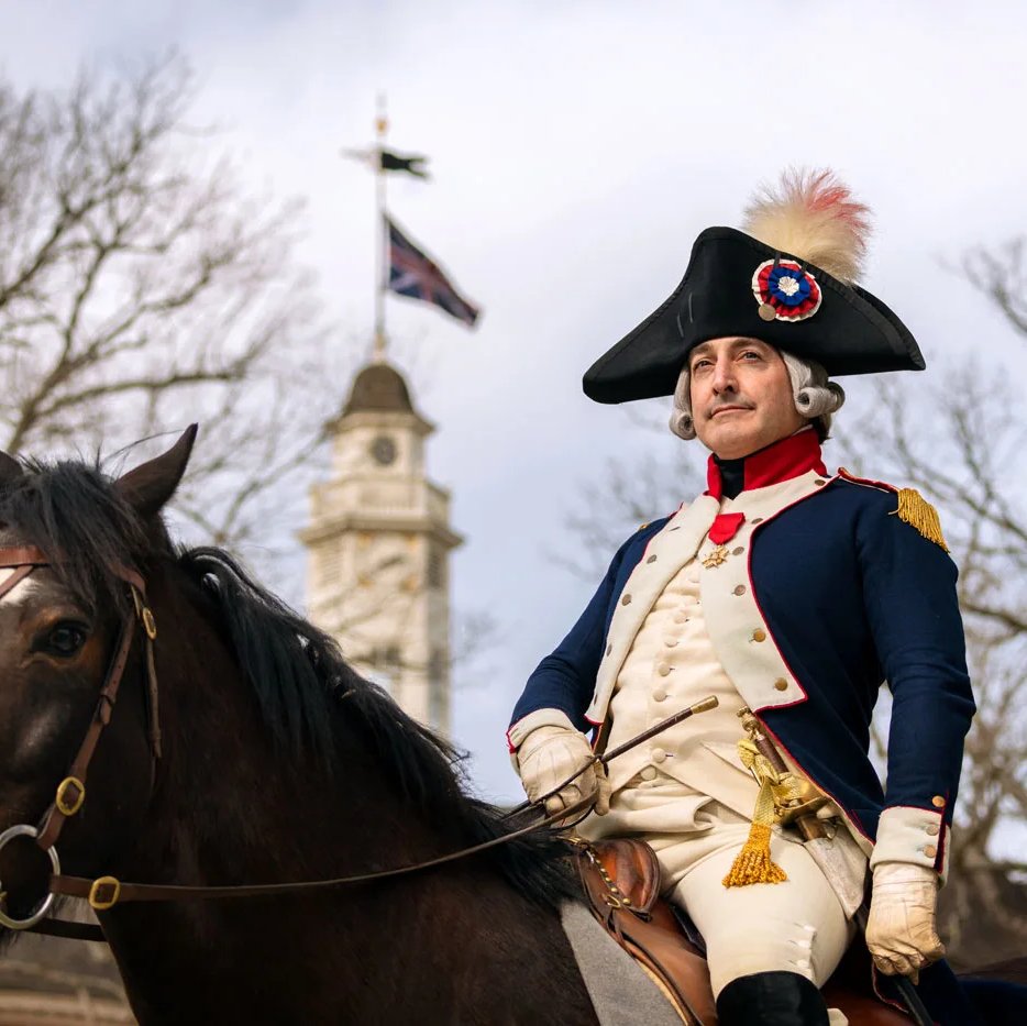 An interpreter dressed as Marquis de Lafayette sits atop a horse in front of the Capitol building.