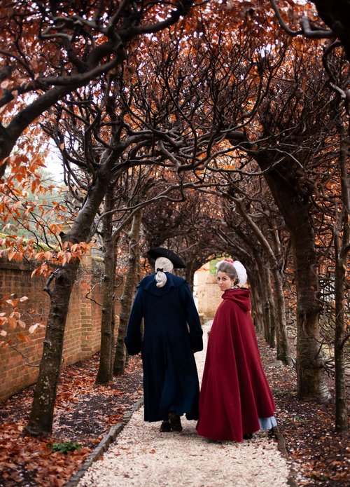 Interpreters dressed as George and Martha Washington walk down a pathway together.