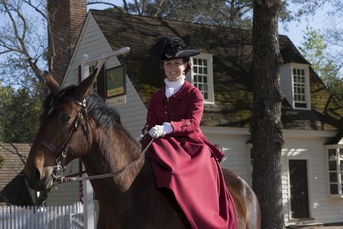 An interpreter dressed as Martha Washington sits atop a horse.