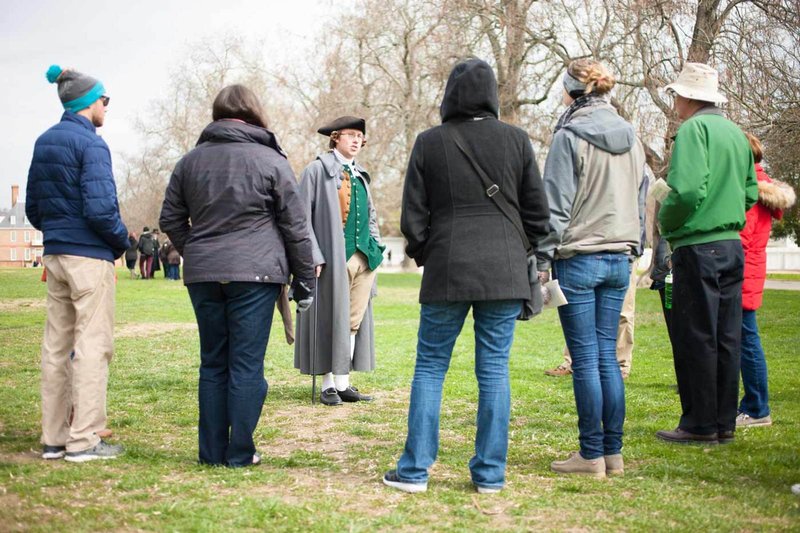 An interpreter dressed as George Mason speaks to a tour group on the Palace Green.