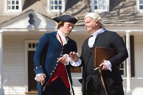 Interpretors dressed as George Wythe and Thomas Jefferson speak to one another in front of the Raleigh Tavern.